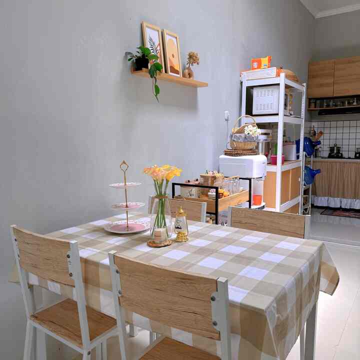 Natural-toned dining room featuring a checkered dining tablecloth, potted plants, and shelves in a cozy atmosphere