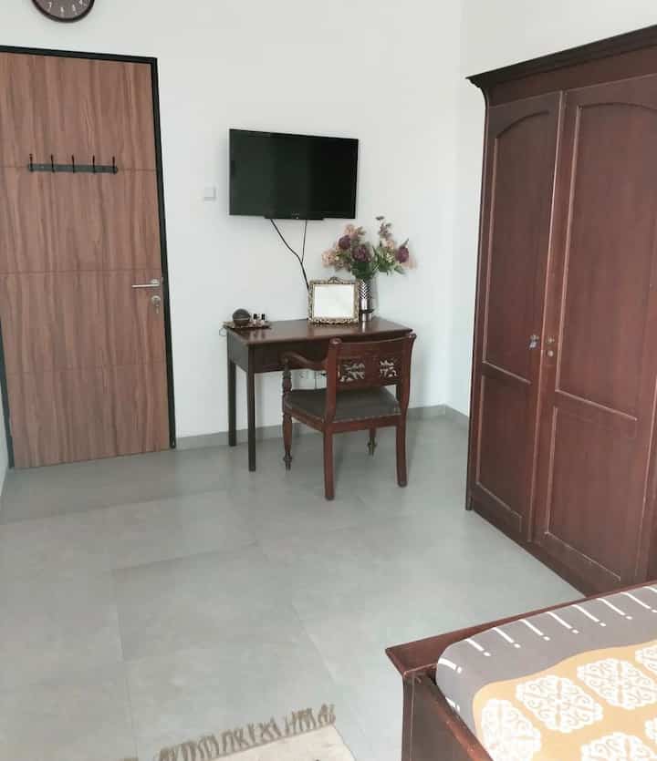 Simple bedroom with white walls and brown wooden furniture including wardrobe, desk, and bed frame