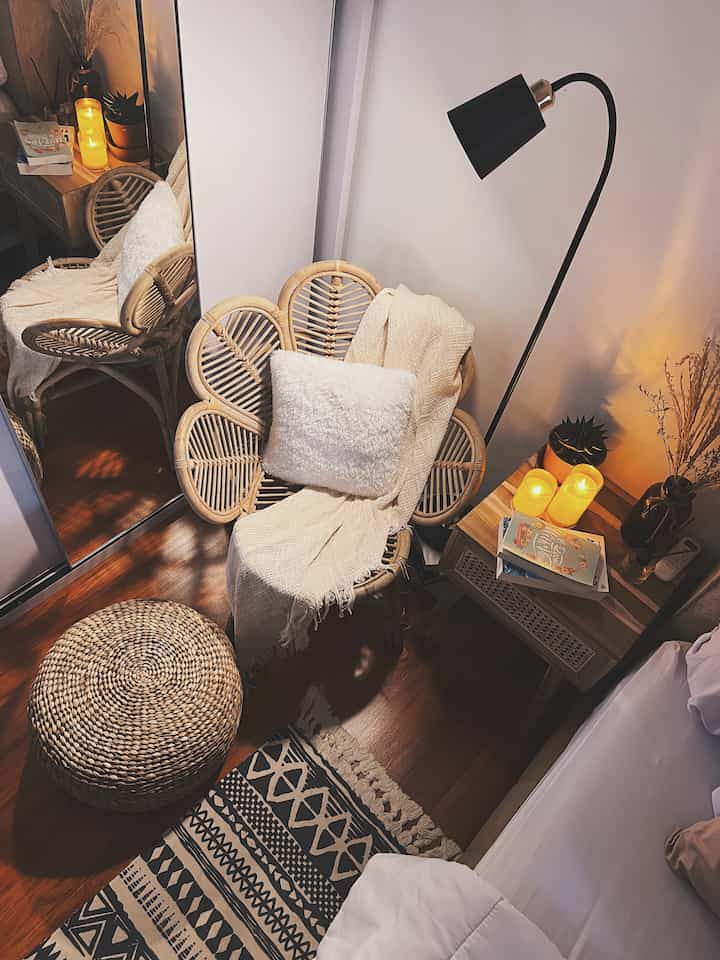 Natural wood-toned bedroom featuring a rattan armchair, patterned rug, and warm lighting creating cozy ambiance