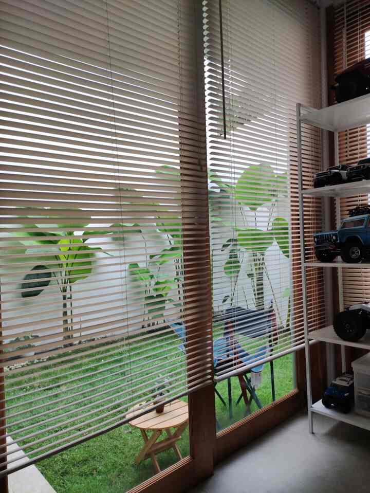 Bright space near balcony with natural wood tones and beige blinds, featuring green plants and a relaxed atmosphere