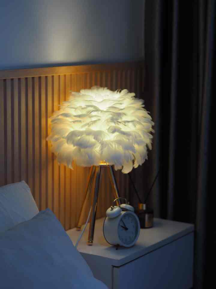 Modern bedroom nightstand space with brown wood panel wall and white feather table lamp
