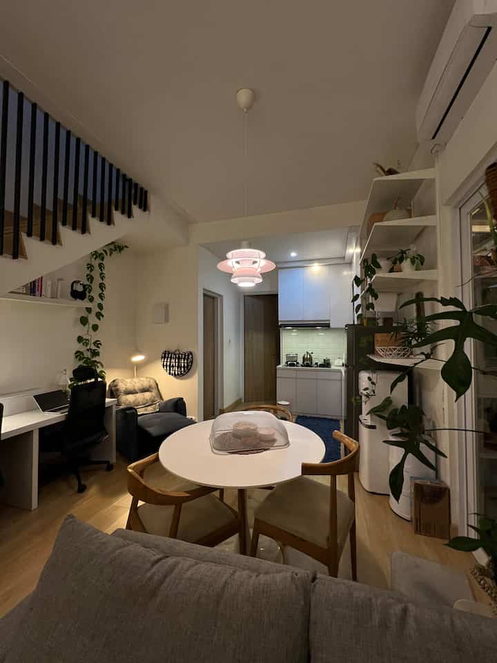 White and wood tone living and dining room featuring pendant light and dining table in a Scandinavian style space