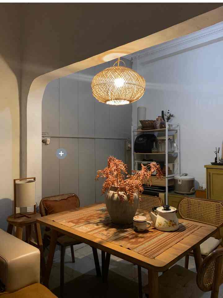 Cozy dining room with warm wood tones and a pendant light, featuring a central vase and table runner