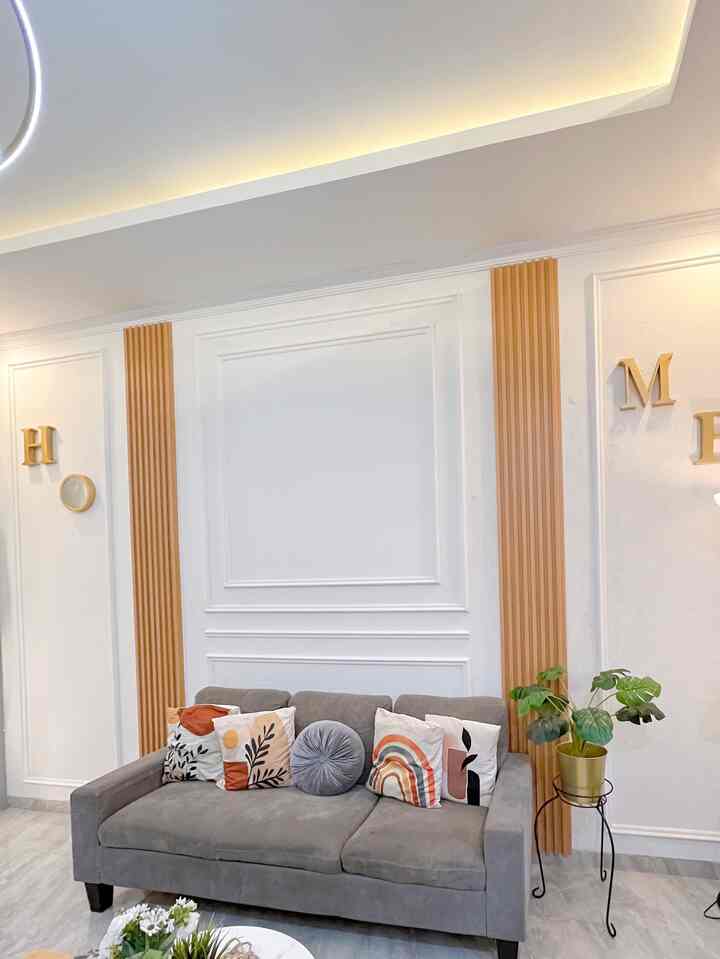 Clean living room featuring a gray sofa and brown wall decor, accented with patterned cushions and a green potted plant