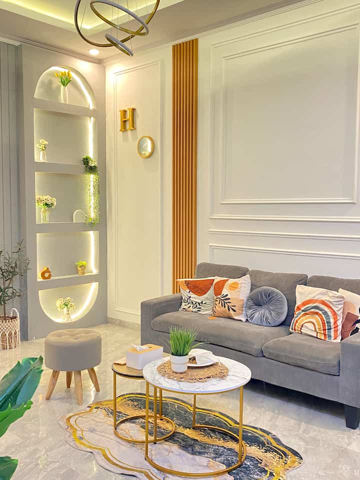 White tone living room featuring a gray sofa and gold-framed coffee tables, natural colors and plants blend into a simple modern space