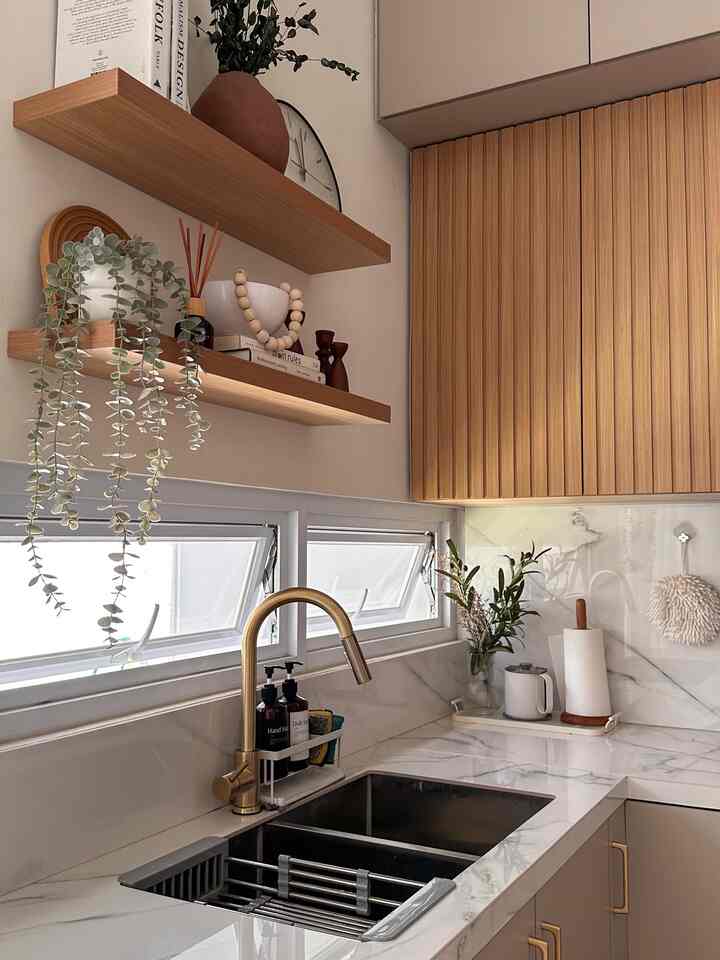 Natural-toned kitchen featuring gold faucet, wooden shelves, and marble countertop creating a cozy atmosphere
