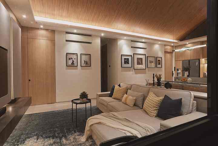 Modern natural living room with wood tones and beige hues, featuring a spacious three-seater sofa adorned with cushions and carpet for a cozy atmosphere