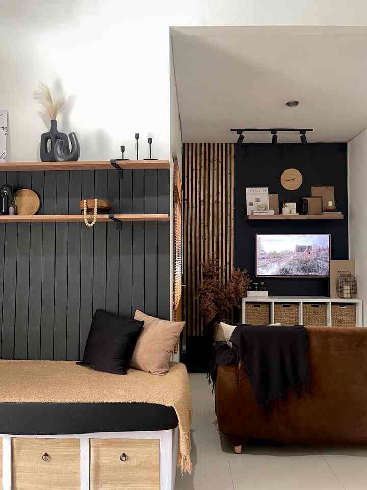 A living room with harmonious black and brown wood tones featuring a sofa, wall shelves, and storage baskets creating a cozy atmosphere