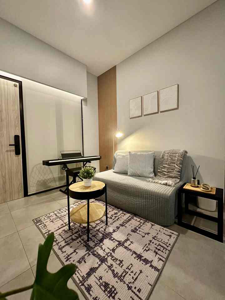 Beige and gray toned small living room featuring wood tone wall panel, cozy carpet, and compact furniture creating a warm atmosphere