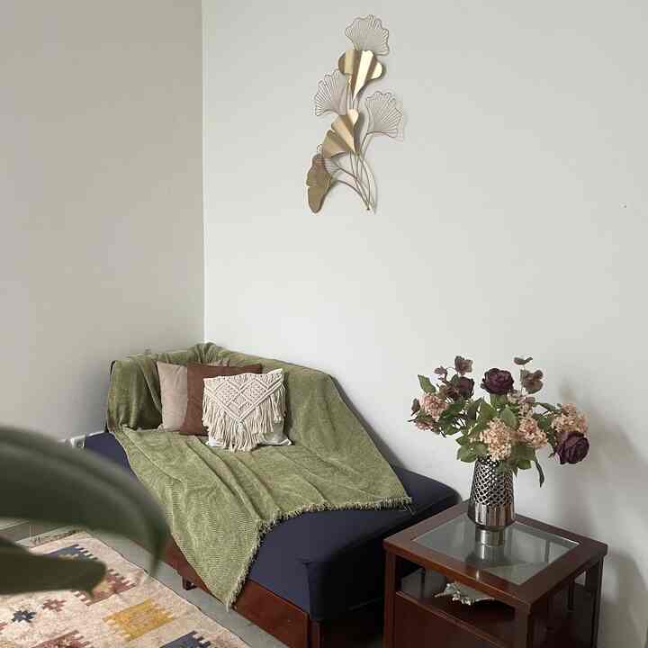 A living room with olive green and navy tones featuring a teal sofa and bronze wall art creating a natural atmosphere