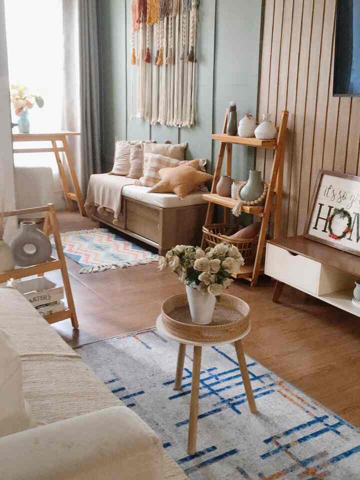 Cozy living room with natural wood tones and carpets, featuring a sofa and decorative shelving creating a warm atmosphere