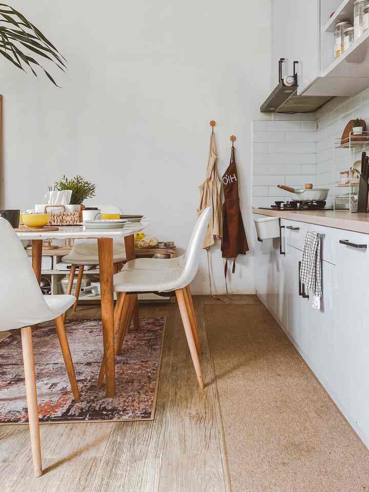 White and wood tone kitchen and dining table, aprons hanging, natural style dining room interior