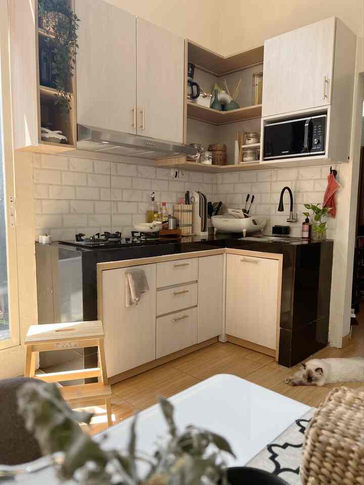 Natural style kitchen with warm wood tones and white color scheme, featuring neat cabinetry and a relaxed pet cat lying on the floor