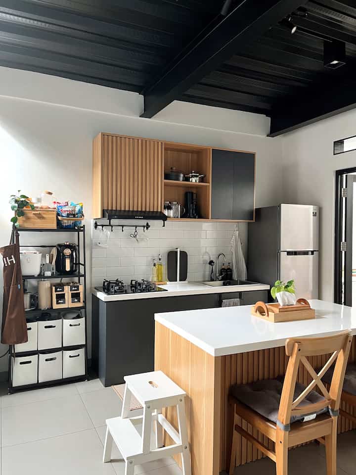 A modern small kitchen in white and wood tones featuring a kitchen island and neatly organized storage cabinets