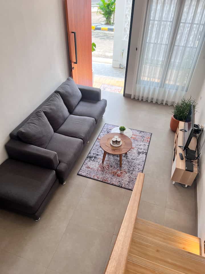 Neutral-toned living room featuring gray sofa and wooden furniture with a spacious feel