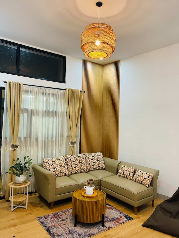 Natural modern living room with wood tones featuring a mustard yellow curtain and a 4-person L-shaped sofa