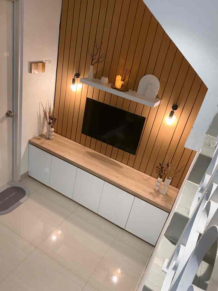 Warm brown and white toned living room featuring a TV mounted on a wooden slat wall and neat cabinetry, creating a simple atmosphere