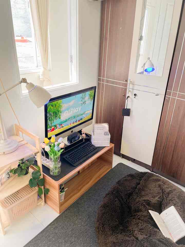 A compact home office in white and brown tones featuring an iMac desk setup and a brown bean bag creating a cozy workspace
