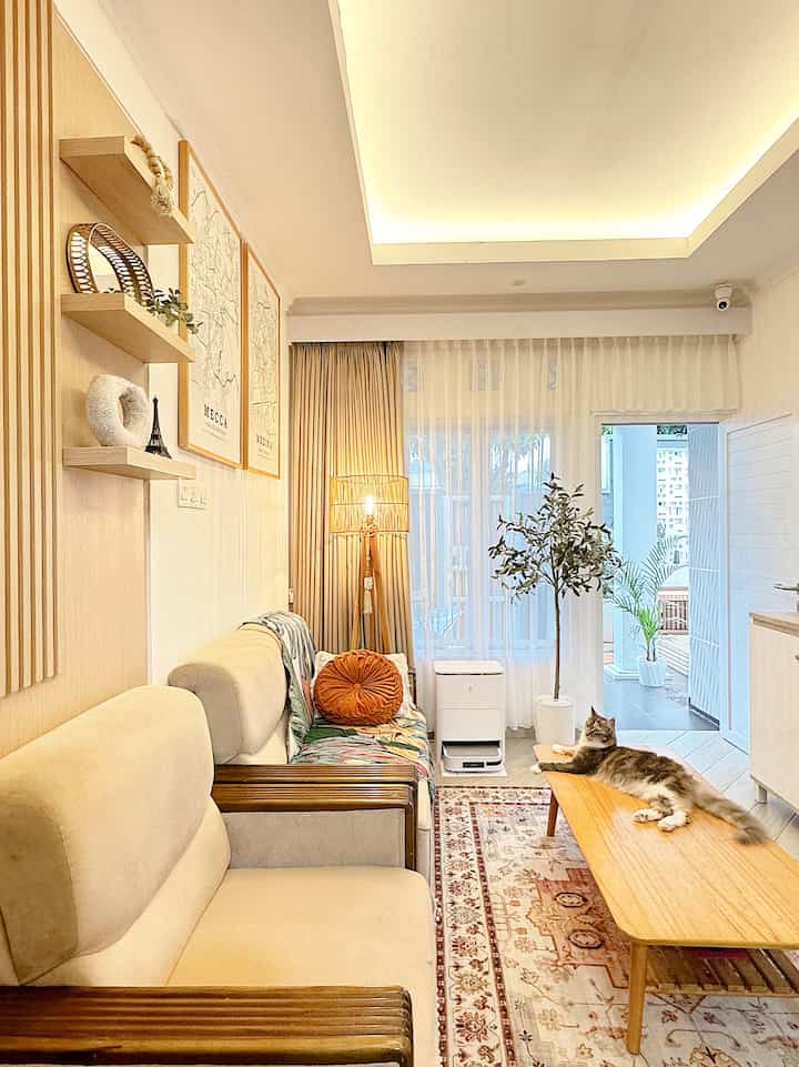 A natural-toned living room featuring beige sofas and wood furniture with a cat lounging on the coffee table