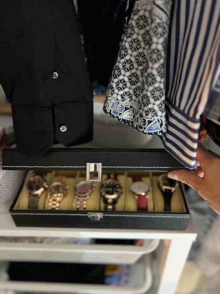 Black and brown toned closet space featuring a watch case with various watches displayed in an organized manner