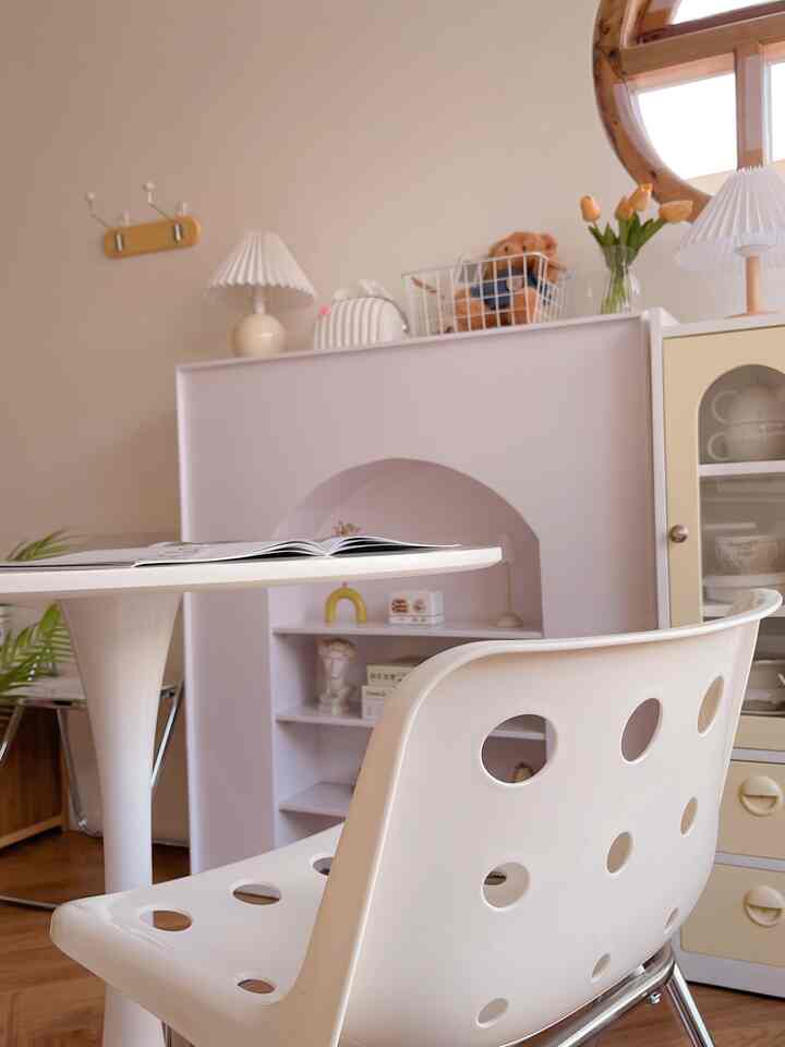 A soft beige and white toned dining room featuring a round dining table and uniquely designed chairs in a clean setting