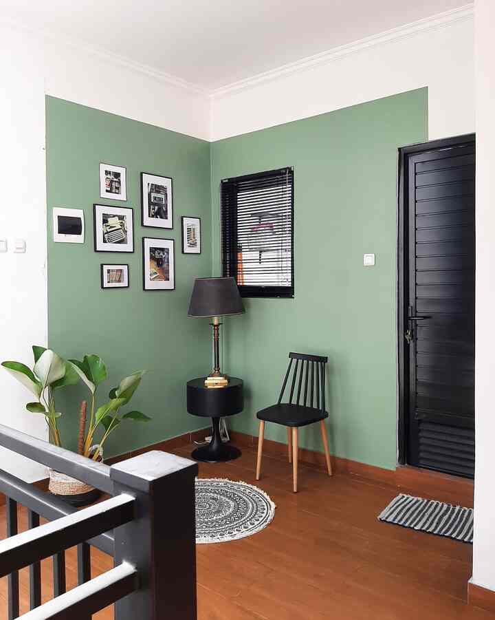 An entrance interior featuring green walls, wood tone floor, black blinds window, and simple furniture elements