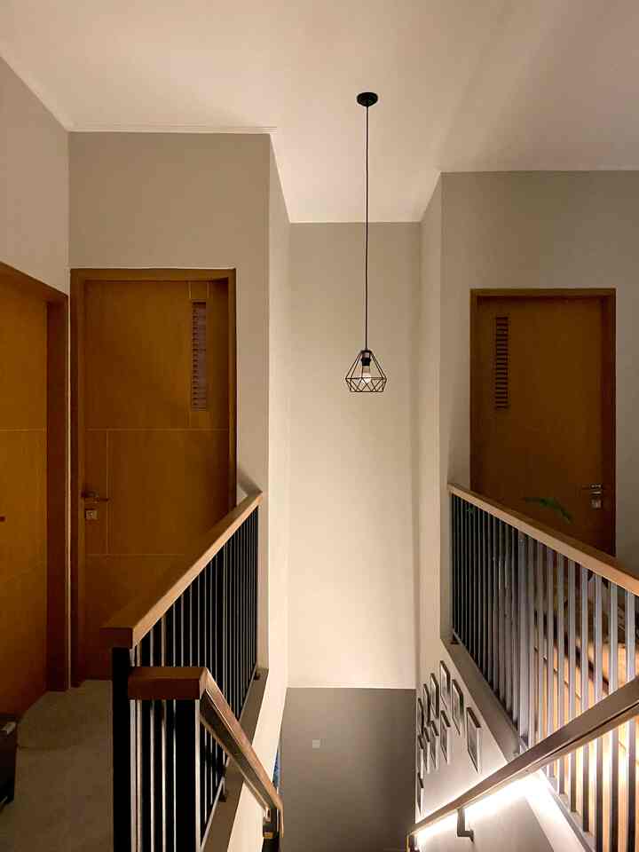 Gray-toned modern stair hallway featuring brown wooden doors, black metal railings, and a central pendant light fixture