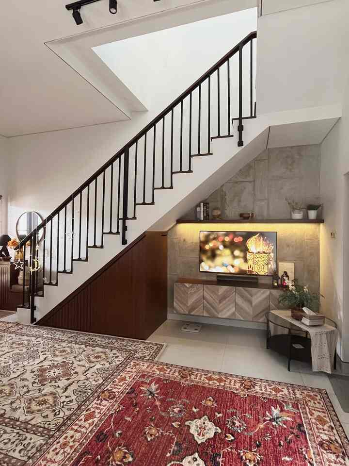 Brown and natural-toned living room featuring decorated stairs and rugs with cozy ambiance