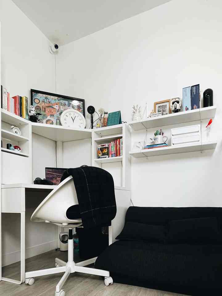 White and black toned small home office featuring a desk and sofa bed in a neat interior