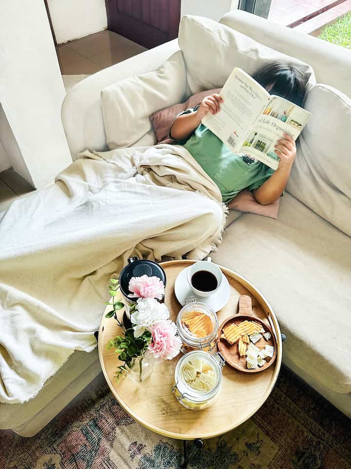 A cozy beige and white toned living room featuring a round coffee table and a child reading a book on a soft sofa