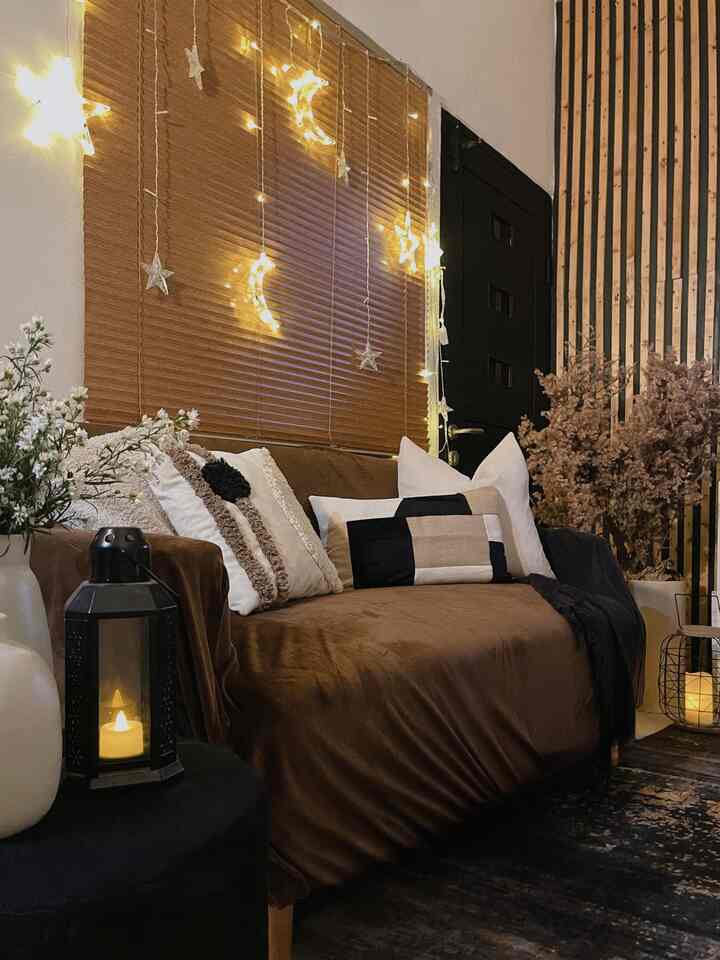 Brown and black toned living room with sofa, cushions, and star-moon lights creating warm, natural atmosphere