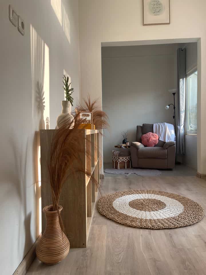 Natural-toned small entrance and reading nook featuring wooden bookshelf and recliner armchair with cozy atmosphere