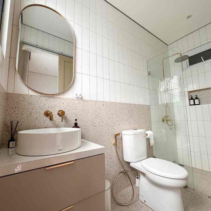 Modern bathroom in white and beige tones featuring gold fixtures and a taupe cabinet, creating a sleek and elegant atmosphere