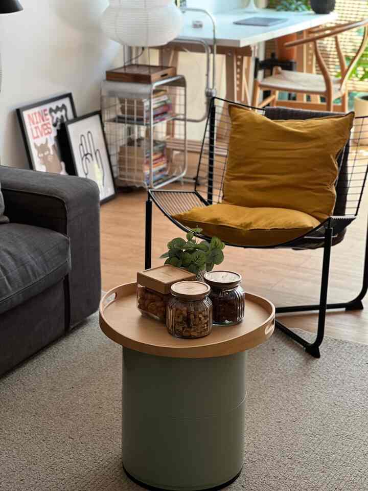 Minimal living room with wood tones and gold cushion, featuring a round side table and dark gray sofa in a cozy atmosphere