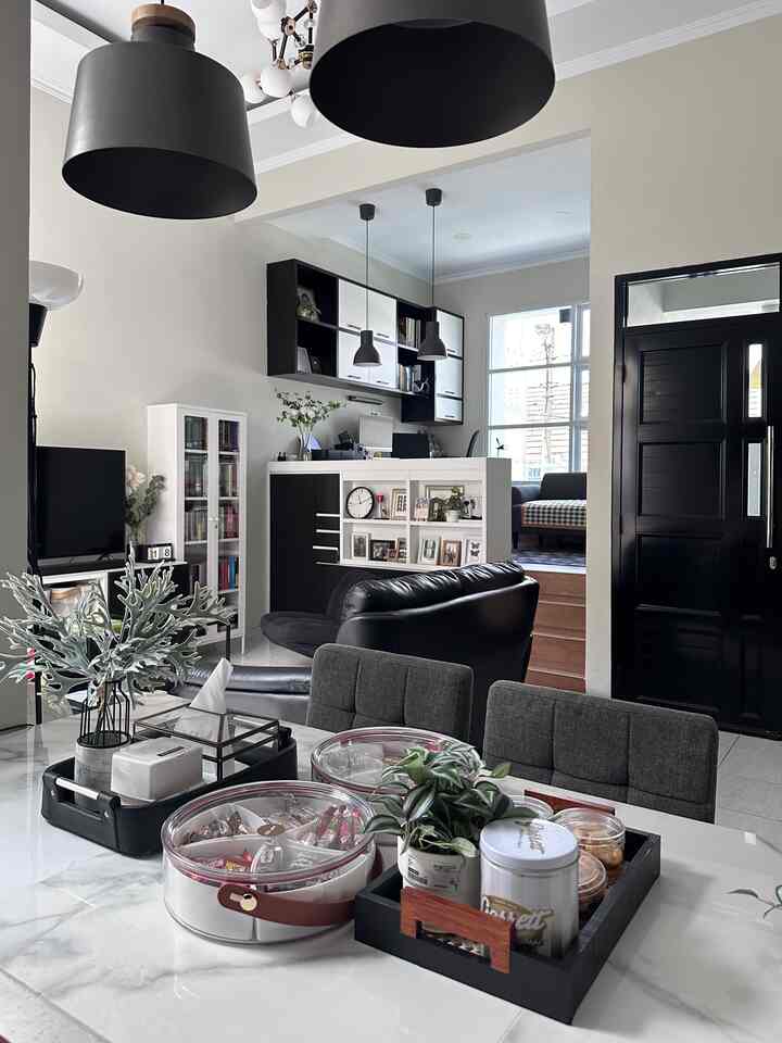 Modern black and white toned dining room and living room with trays on dining table and pendant lights creating a clean space