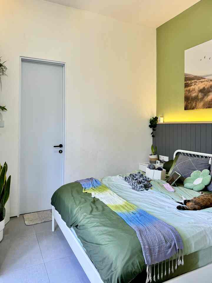 White and green toned bedroom featuring a white bed with multi-colored throw blanket, offering a cozy atmosphere