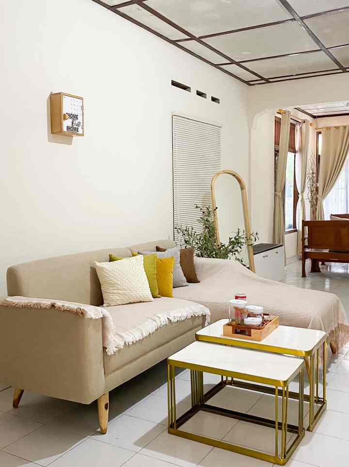 Warm beige and white toned living room featuring colorful cushions and a standing mirror with a cozy atmosphere