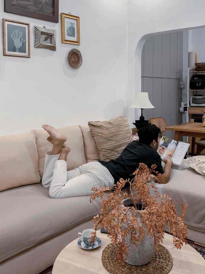 Beige-toned living room featuring a large sofa, table lamp, framed art, and dried foliage centerpiece, creating a cozy atmosphere.