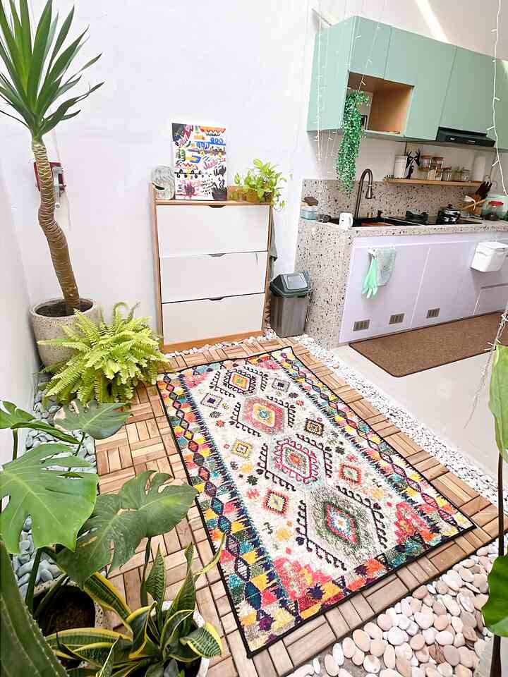 Natural white-walled dining space featuring colorful carpet and abundant green plants with a cozy natural atmosphere