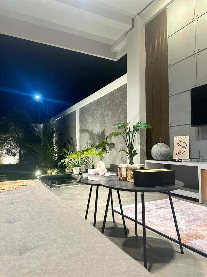 Natural tone living room featuring gray sofa, bohemian rug, plants, and table lamp with cozy relaxing atmosphere