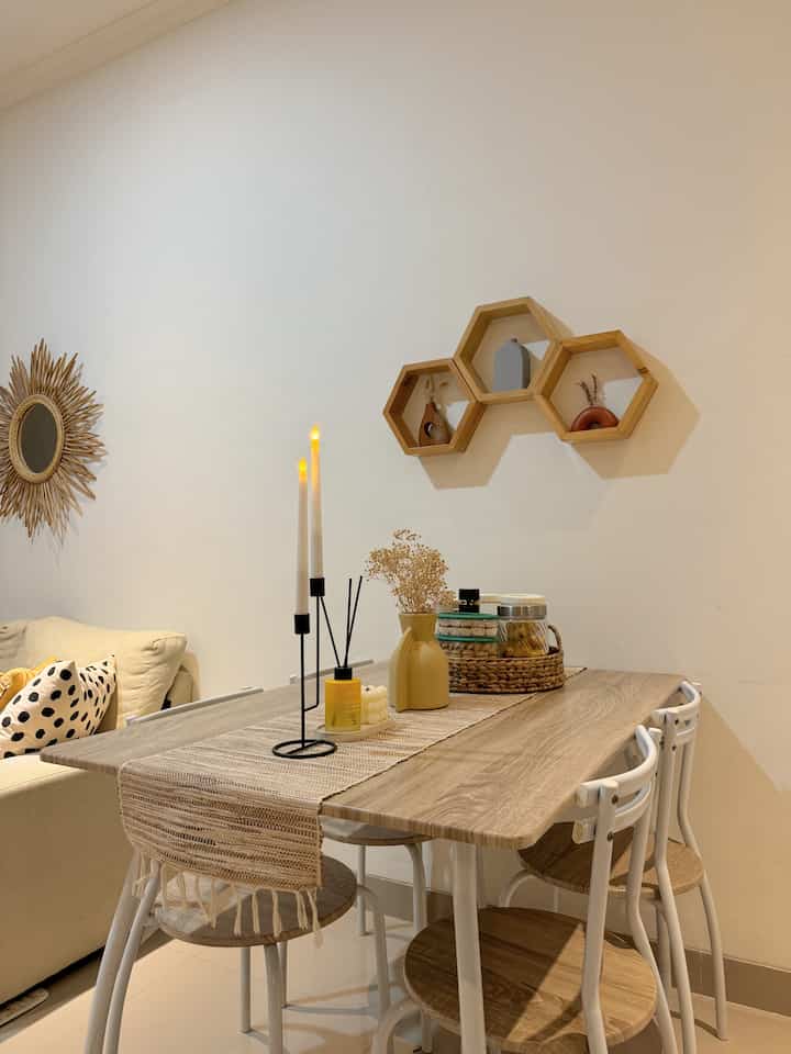 Natural color and wood tone dining room featuring a table runner, candles, and diffuser with a cozy and warm atmosphere
