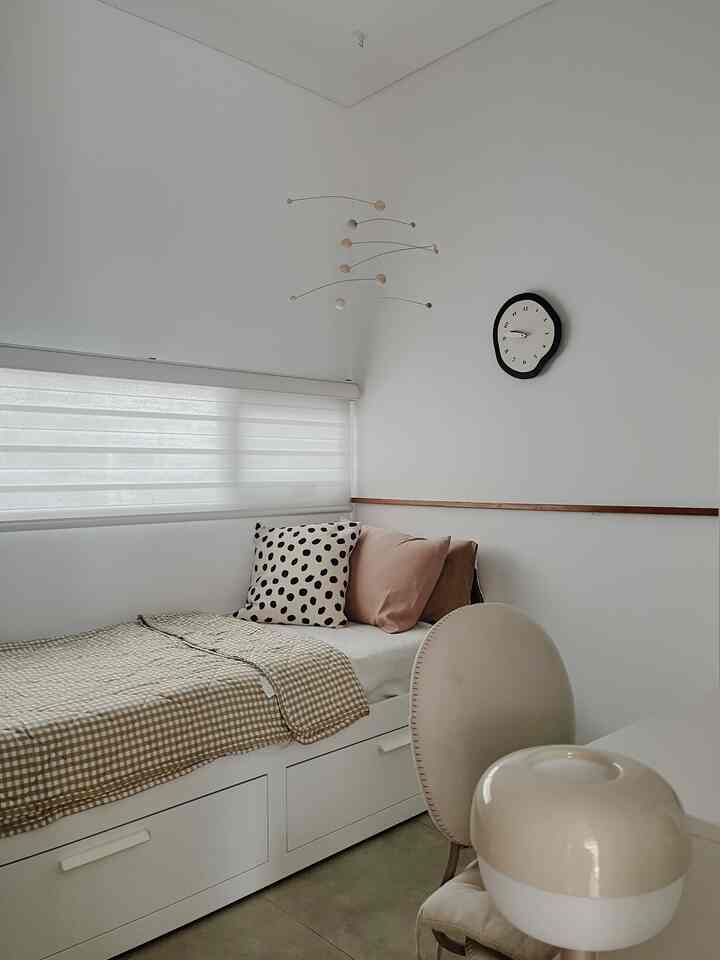 A white and beige bedroom featuring a bed, cushions, and blinds with a simple and natural atmosphere
