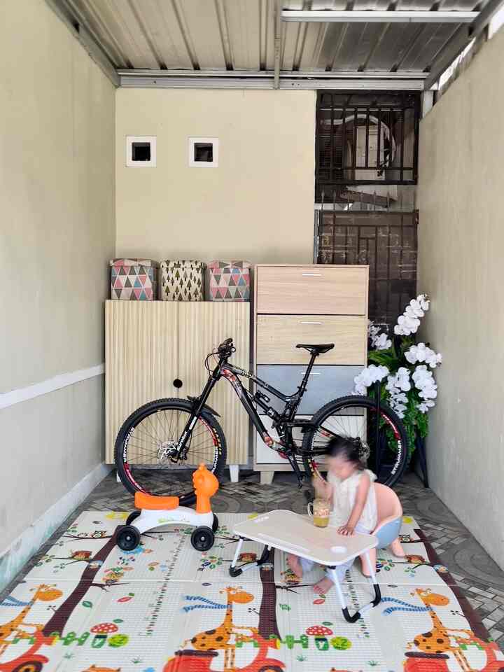 Menciptakan ruang bermain bagi anak namun tetap menjaga estetika. Sejak awal mengisi perabotan di rumah ini, aku dan suami sangat memperhatikan pemilihan furnitur agar ramah anak. Terutama meja & kursi diutamakan menggunakan yg bersudut tumpul supaya anak bisa leluasa bergerak meskipun space ruangan terbatas dan tidak membahaykan. 
Area bermain anakku aku bagi menjadi dua. Yang pertama memanfaatkan Garasi Mobil dan area Enterence saat masuk rumah. Biasanya anak-anakku akan bermain di Garasi saat kedatangan banyak anak tetangga yg bermain ke rumah. Di sini mereka bisa leluasa bermain karena area Garasi dan teras cukup luas. Aku biasanya meletakkan beberapa box mainan, playmate, baby chair, dan sepeda anak. Sedangkan untuk kesehariannya anakku akan bermain di dalam rumah. Di bagian enterence kami memiliki sedikit space untuk meletakan sofa tatami, box mainan dan juga meja TV. Di bagian enterence ini kami tidak banyak meletakkan barang atau pajangan karena akan mebuat ruang bermain anak semakin sempit. Untuk menciptakan ruang bermain anak yang estetik, kami memilih menggunakan karpet, box mainan, dan kursi lesehan bernuansa Japandi dengan warna-warna dark wood. #KidsFriendlyHome #RumahRamahAnak #FamilyFriendlyDesign
