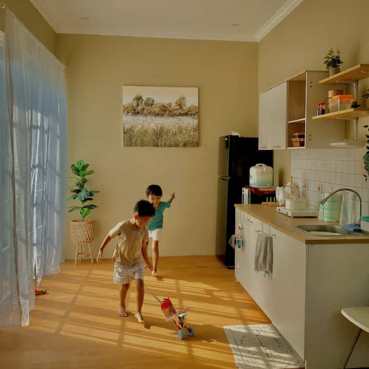 Warm beige natural kitchen space featuring two children playing on center floor in a family-friendly environment