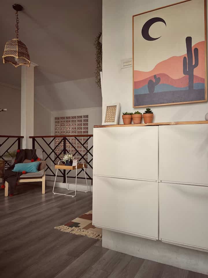 Cozy entrance area featuring warm wood tones and white shoe cabinet, armchair, and wall decor with framed art