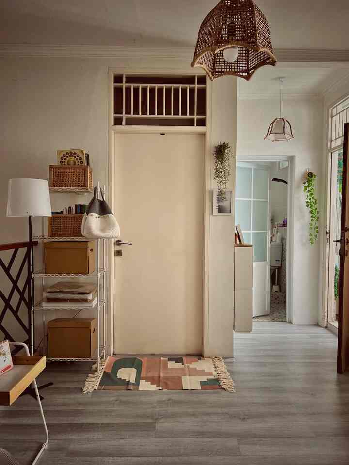 White and beige-toned entrance with visible balcony, featuring rattan lamps and storage shelving in a natural atmosphere