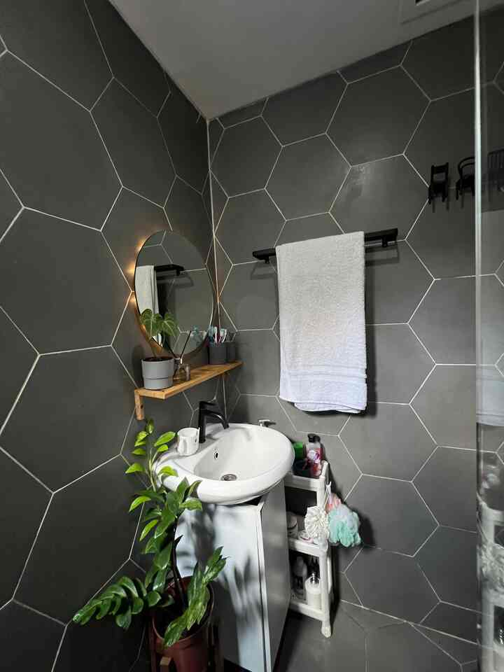 Untuk menyiasati ukuran kamar mandi yang kecil, penggunaan rak tarik dan rak yang menempel di dinding membantu untuk menyembunyikan serta memperlihatkan perkakas kamar mandi. Aksen kayu dan tanaman membuat nuansa kamar mandi lebih homy dan personal.
#InspirasiKamarMandi #BathroomInspo #DesainKamarMandi #KamarMandiMonokromatik #MonochromeBathroom #SmallBathroom #Wastafel