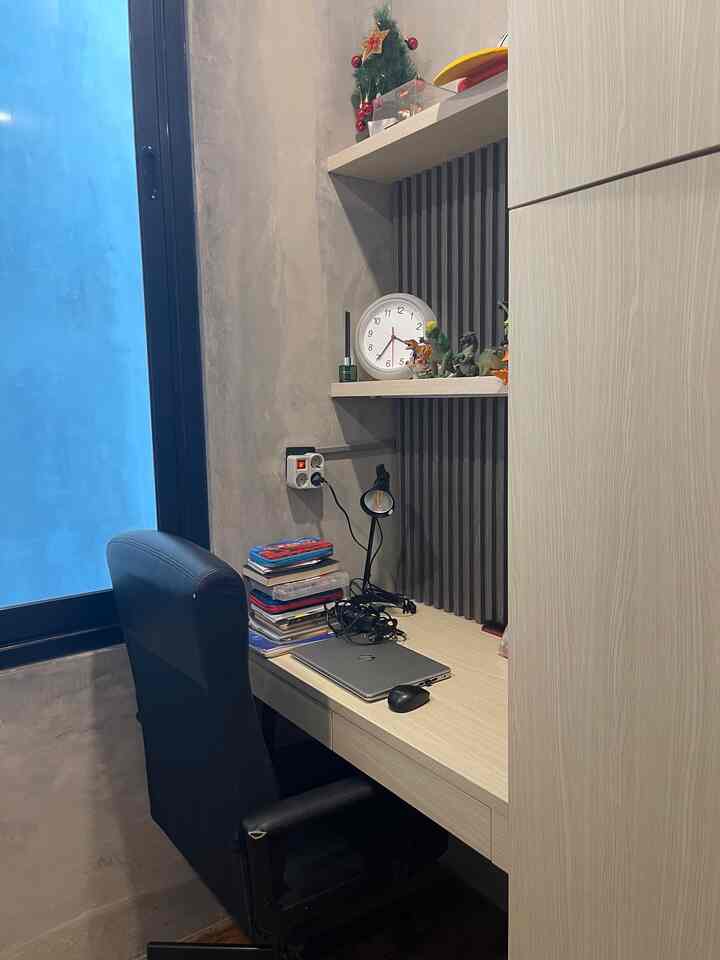 White and black toned home office space featuring a desk, office chair, clock, and decorations on wall shelves in a compact work area