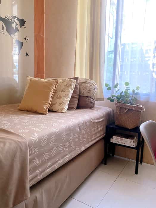 Beige and wood-tone kids' bedroom featuring a simple nightstand and a potted plant, creating a bright and cozy atmosphere