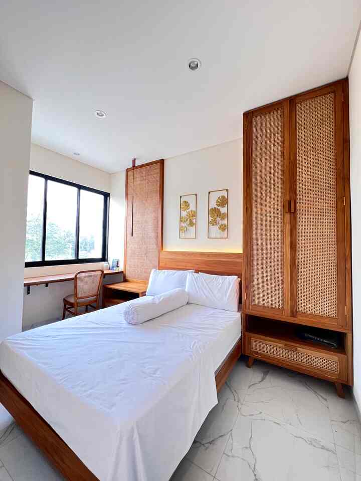Compact bedroom featuring natural wood tone furniture and white elements, accented by rattan textures and clean layout